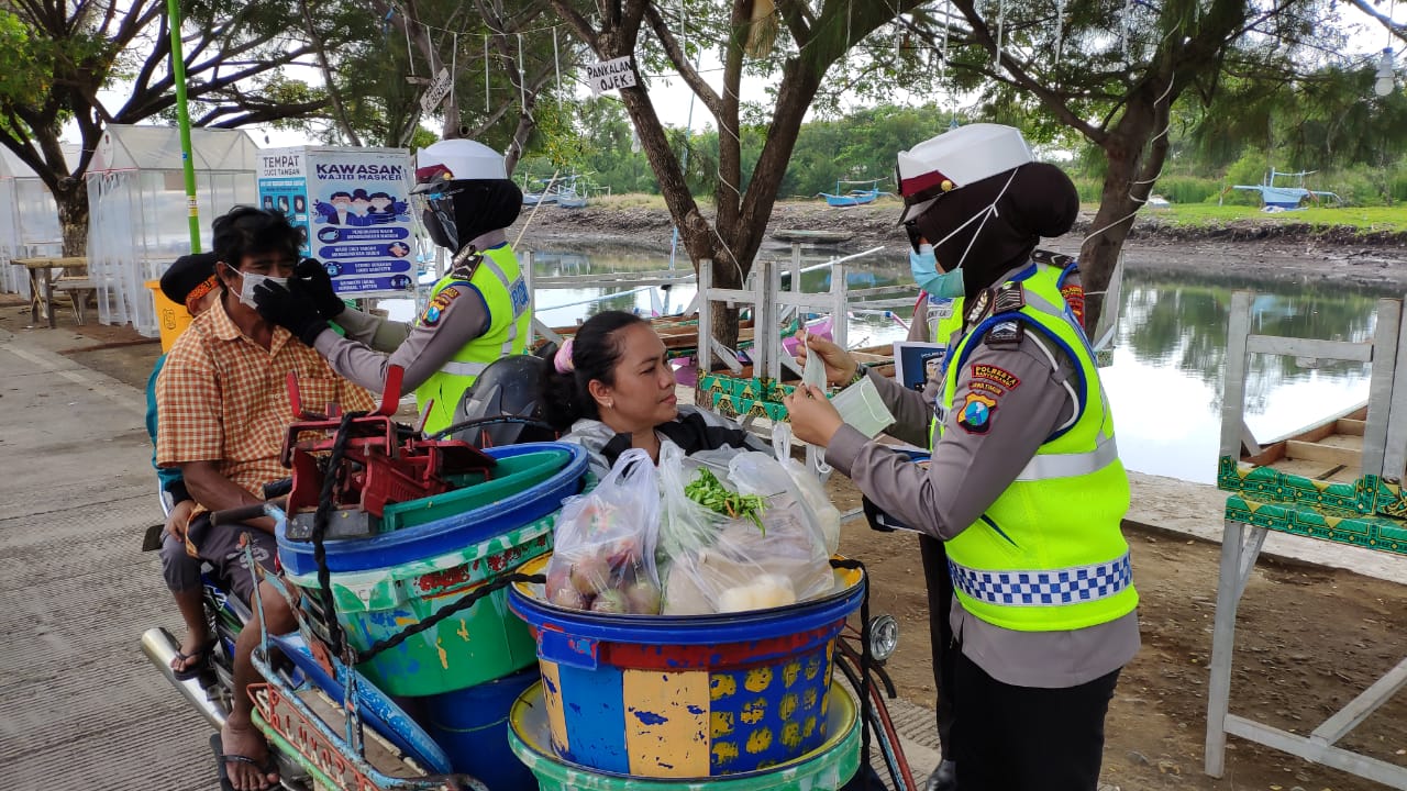 Anggota Satlantas Polresta Banyuwangi memberikan masker pada warga yang tidak mengenakan masker di Pantai Boom, Minggu, 20 September 2020. (Foto: Muh Hujaini/Ngopibareng.id)