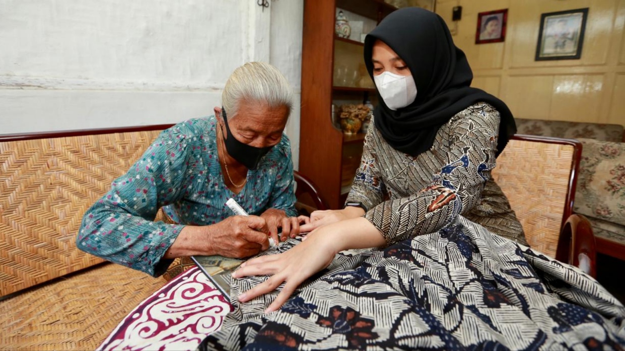 Kulsum mbubuhkan tanda tangan pada batik yang dihadiahkan pada Ipuk Fiestiandani. (Foto: Istimewa)