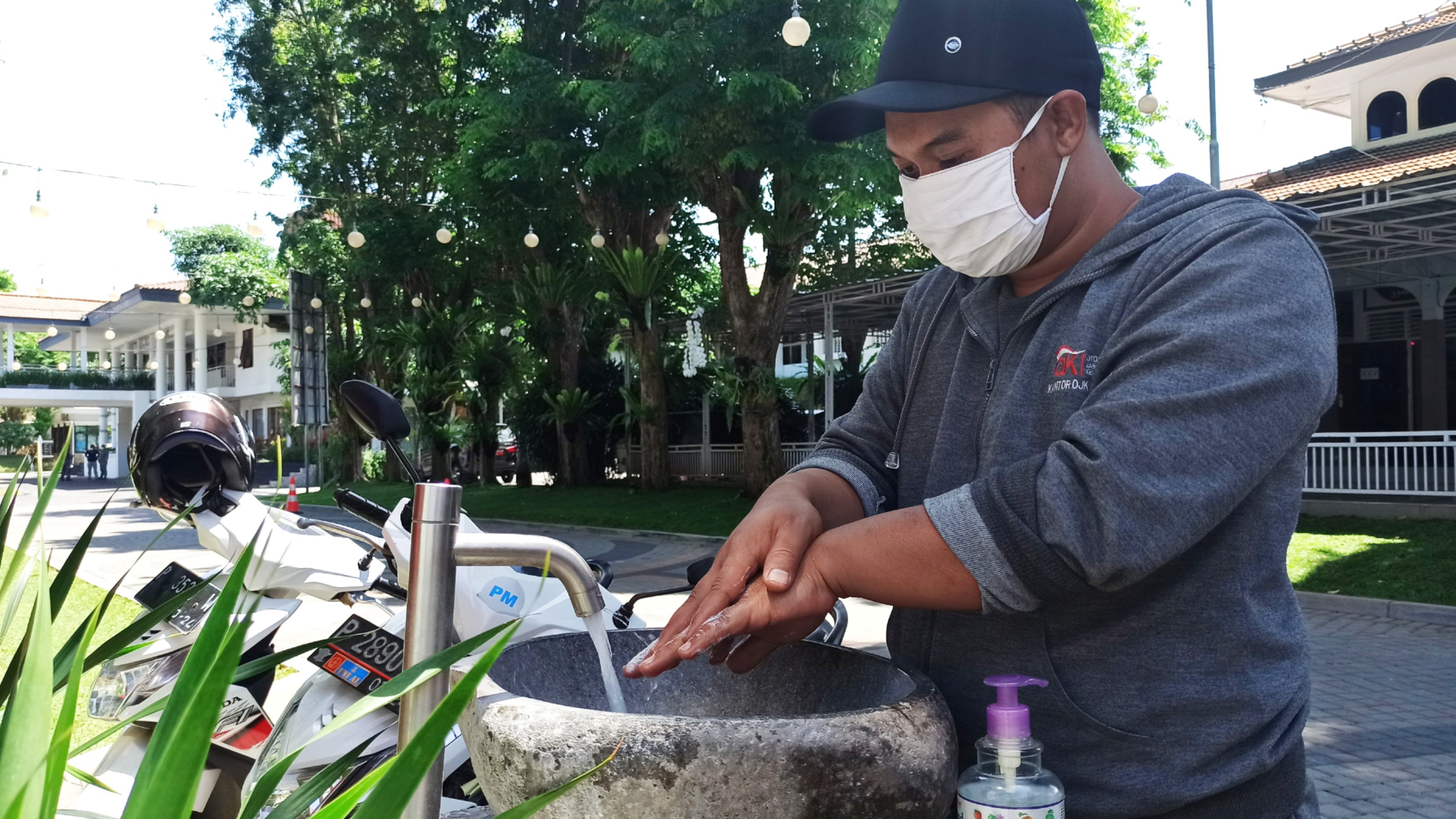 Salah seorang warga sedang mencuci tangan sebelum masuk ke kompleks Pemkab Banyuwangi, Jawa Timur. (Foto: Muh Hujaini/Ngopibareng.id)