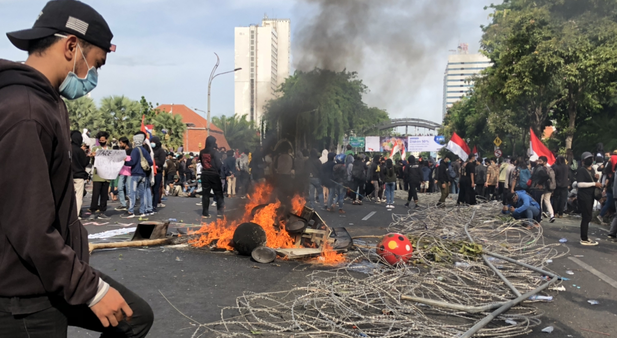 Tampak seorang pemuda, tengah menginjak pagar pembatas yang sudah dirusak massa. (Foto: Andhi Dwi/Ngopibareng.id)