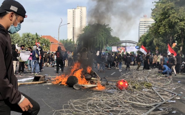 Seorang pemuda tengah menginjak pagar pembatas yang sudah dirusak massa. (Foto: Andhi Dwi/Ngopibareng.id)