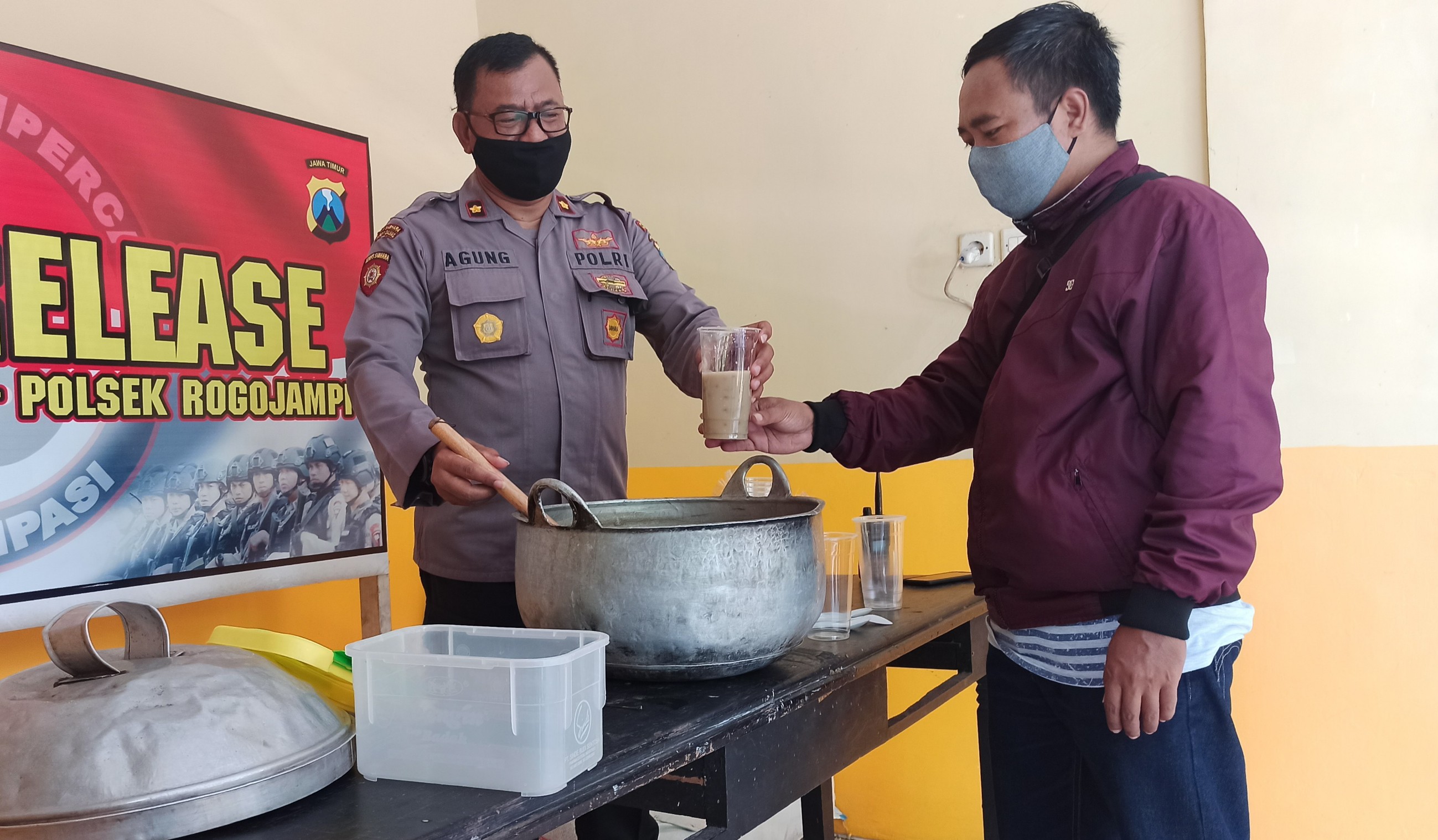 Petugas Polsek Rogojampi memberikan bubur Kacang Hijau pada salah satu warga yang datang ke tempat itu (foto: Muh Hujaini/Ngopibareng.id)