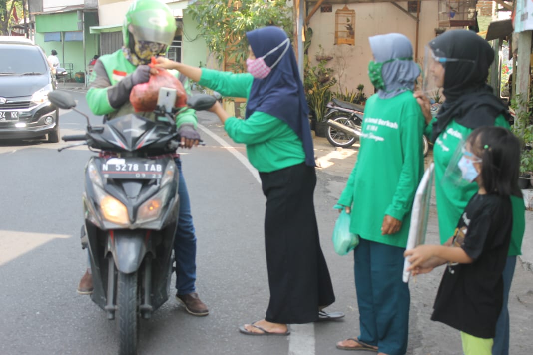 Ibu-ibu warga Manyar Sabrangan membagikan sayur-sayuran kepada para pengguna jalan. (Foto: Asmanu/Ngopibareng.id)