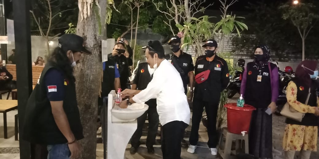 Cabup Gresik Moh Qosim tampak mencuci tangan didampingi Ketua Panwascam Bungah Didik Hendriyono sebelum memulai kampanye. (Foto: Azharil Farich/Ngopibareng.id)