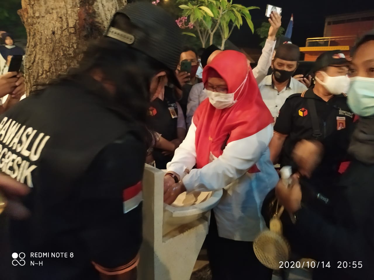 Cawabup Gresik Aminatun Habibah tampak mencuci tangan didampingi Ketua Panwascam Bungah Didik Hendriyono sebelum memulai kampanye. (Foto: Azharil Farich/Ngopibareng.id)