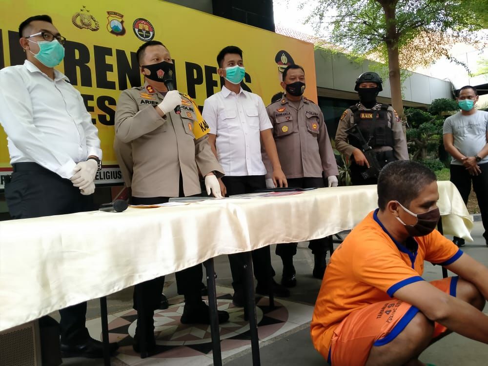 Tersangka Misbahul Munir tampak jongkok di depan saat Kapolres Gresik AKBP Arief Fitrianto didampingi Kasat Reskrim AKP Bayu Febrianto Prayoga memberikan keterangan kepada awak media. (foto: Azharil Farich/ngopibareng.id) 