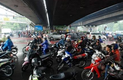 Ilustrasi pengendara sepeda motor berteduh di bawah fly over saat hujan. (Foto: Twitter)