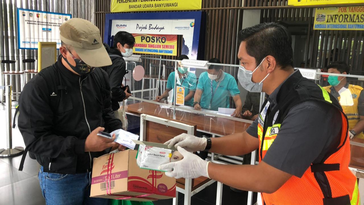 Petugas Bandara Banyuwangi membagikan masker pada penumpang. (Foto: Istimewa)