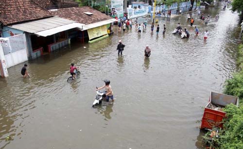 Pengendara sepeda motor mendorong kendaraannya saat menerobos jalan yang tergenang banjir di kawasan jalan raya Gempol, Pasuruan, Jawa Timur, Senin. (Foto:Antara/Umarul Fauq)