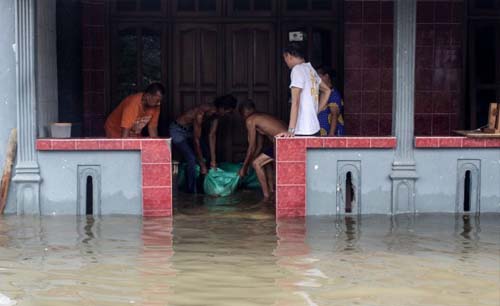 Warga menutup celah pintu rumahnya dengan karung berisi pasir saat banjir merendam sebagian kawasan Kecamatan Gempol, Pasuruan,  Jawa Timur, Senin. (Foto:Antara/Umarul Faruq)