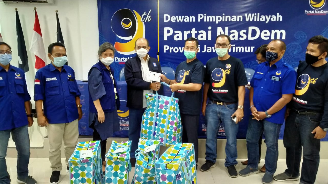 Ketua Bappilu DPP NasDem Teritorial IV Jawa, Dossy Iskandar secara simbolis menyerahkan bantuan paket sembako kepada Ketua DPD NasDem Surabaya Robert Simangunsong untuk dibagikan ke warga. (Foto: Fariz Yarbo/Ngopibareng.id)