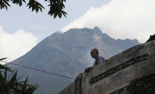 Status Gunung Merapi naik dari Waspada menjadi Siaga, tetapi warga di sekitar masih tenang-tenang saja, seperti seorang warga yang ada di Klakah, Selo, Boyolali, Jawa Tengah, Rabu siang. Latar belakang Merapi yang erupsi. (Foto:Antara/Aloysius Jarot Nugroho)