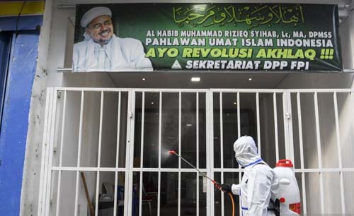 Petugas Polda Metro Jaya dengan mengenakan hazmat menyemprotkan cairan disinfektan di kawasan Petamburan III, Jakarta Pusat, Hari Minggu. (Foto:Antara/M Risyal Hidayat)