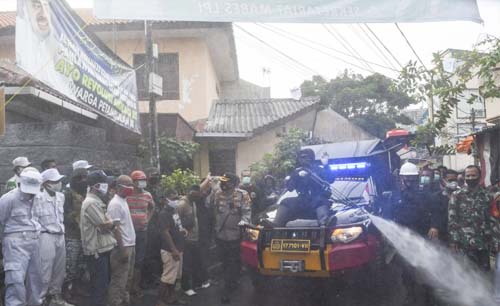Sejumlah anggota kepolisian Polda Metro Jaya dengan mengenakan hazmat menyemprotkan cairan disinfektan di kawasan Petamburan III, Jakarta Pusat, Hari Minggu. (Foto:Antara/M Risyal Hidayat)