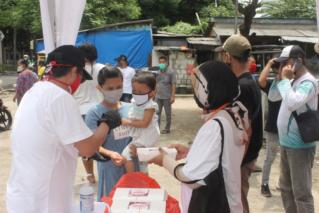 Warga Jakarta Barat sedang antri untuk mendapat makan siang gratis yang dibagikan DNR Corporation di jalan Budi Raya. (Foto: Asmanu/Ngopibareng.id) 