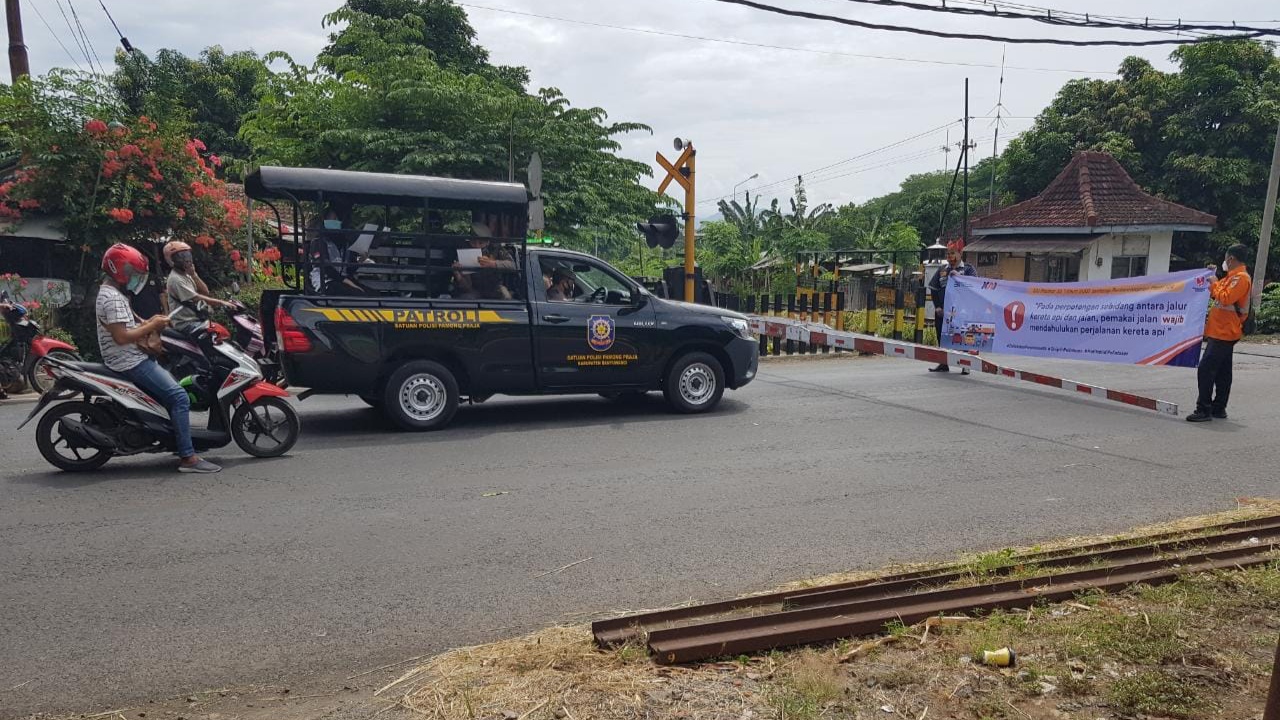 Petugas PT KAI membentangkan spanduk sosialisasi keamanan di jalur perlintasan sebidang JPL 17, Giri, Banyuwangi. (Foto: Istimewa)