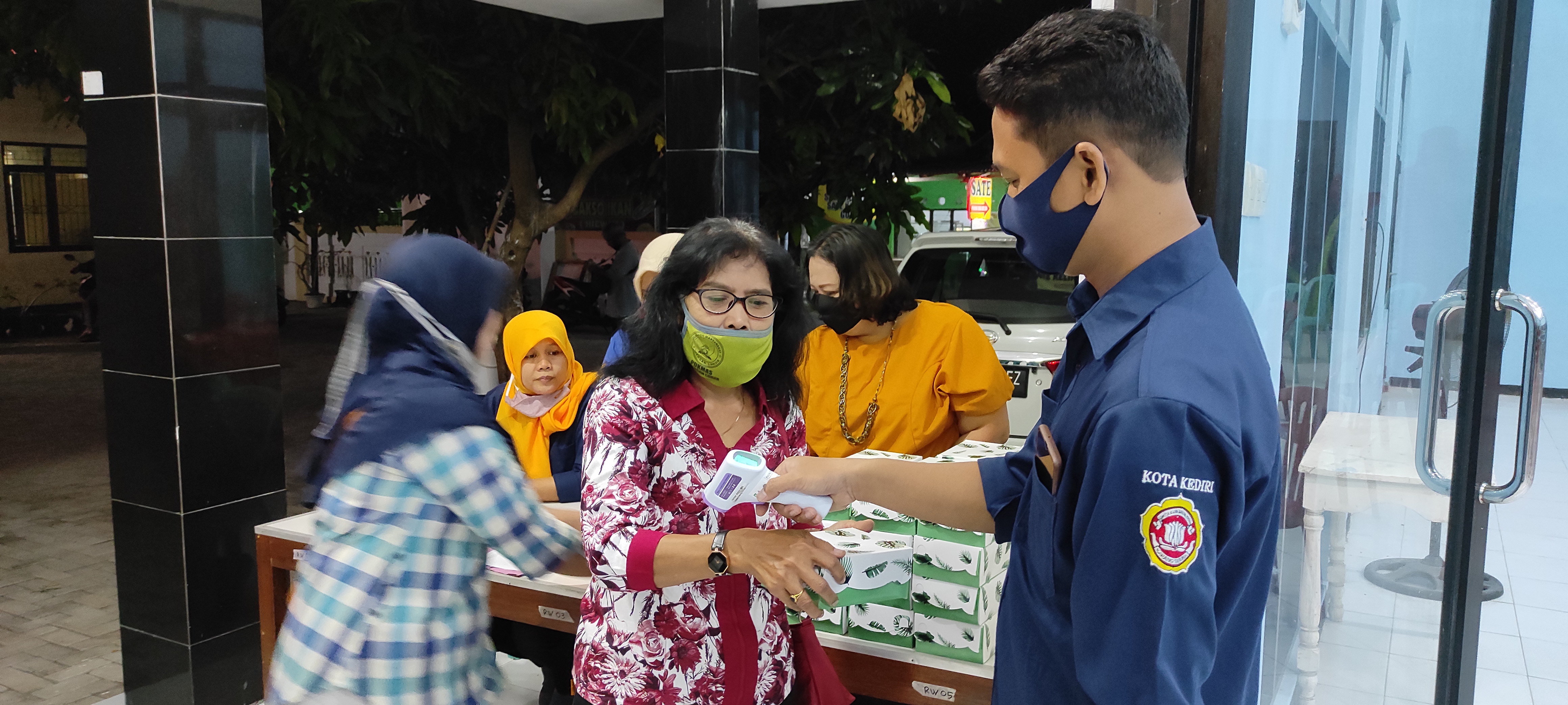Pemeriksaan suhu badan oleh generasi milenial Karang Taruna Kelurahan Burengan. (Foto: Fendi/ngopibareng.id) 