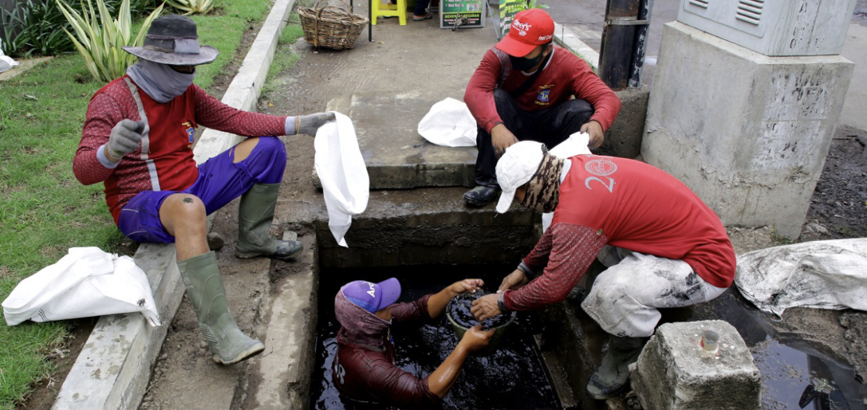 Petugas DPUBMP Kota Surabaya melakukan pengerukan lumpur di gorong-gorong. (Foto: Dok. Humas Pemkot Surabaya)