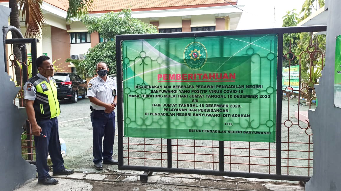 Petugas keamanan Pengadilan Negeri Banyuwangi berjaga di pintu masuk. Tampan papan pengumuman terkait penutupan pelayanan. Dan persidangan di Pengadilan Negeri Banyuwangi (foto:Muh Hujaini/Ngopibareng.id)