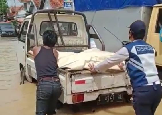 Petugas Dishub Bangkalan mendorong mobil mogok di Blega, Bangkalan akibat banjir. (Foto: BPBD Bangkalan)