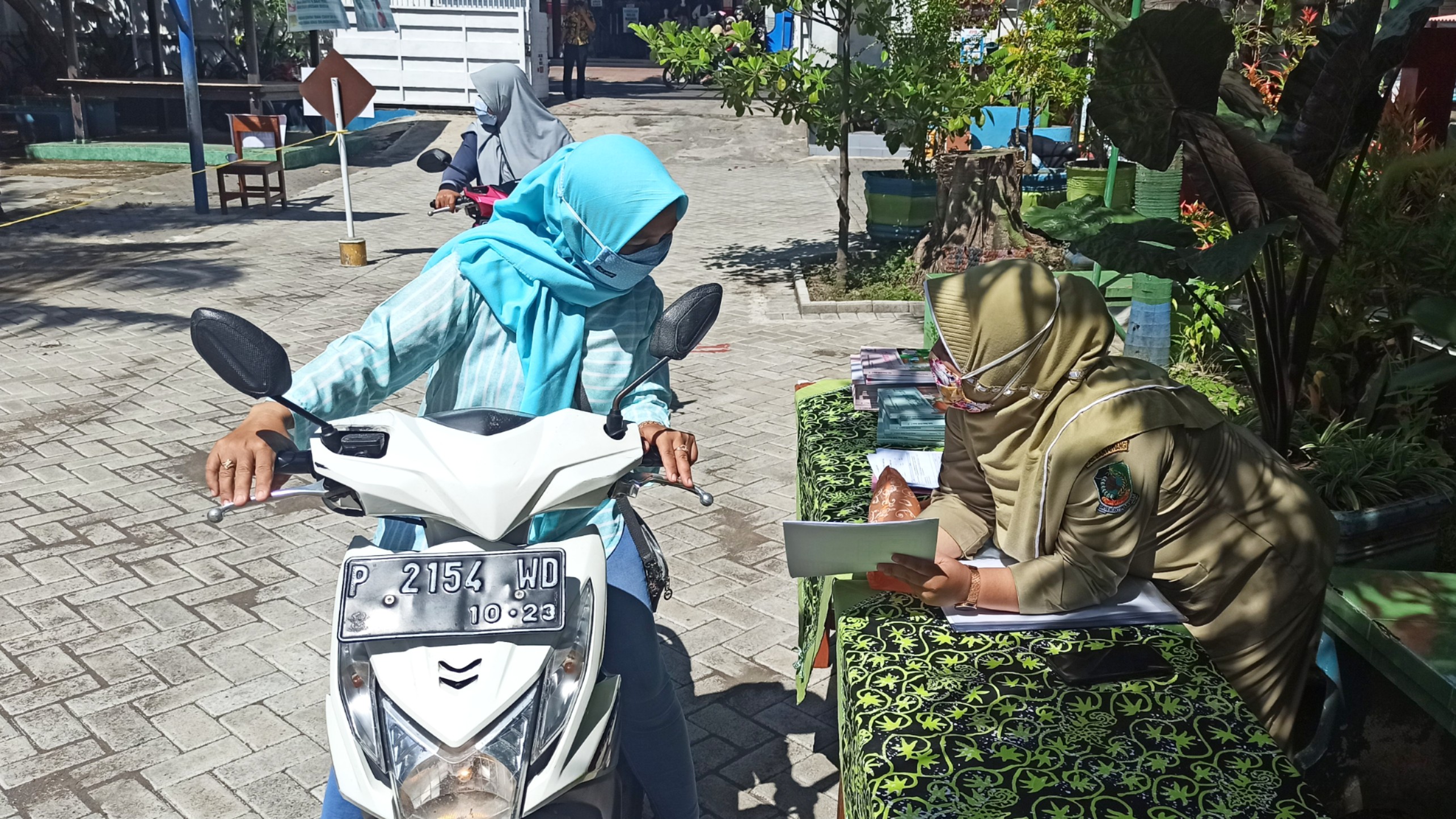 Seorang wali murid mendapatkan penjelasan tentang capaian prestasi anaknya sebelum menerima rapor secara Drive thru. (Foto: Muh. Hujaini/Ngopibareng.id)