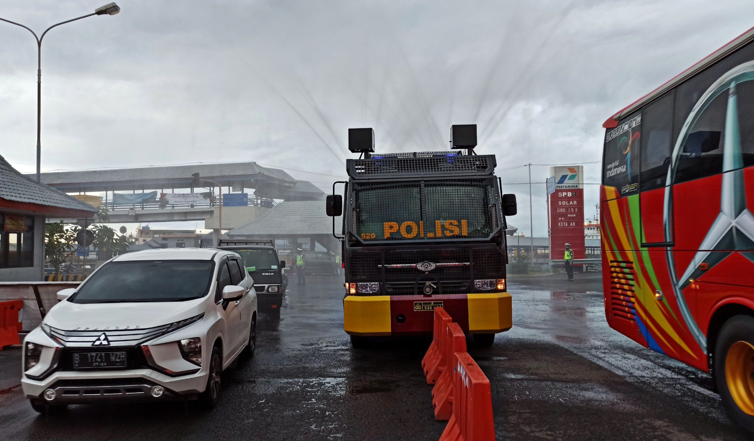 Water Canon milik Polresta Banyuwangi menyemprot kendaraan yang datang dari Bali dengan disinfektan dipintu keluar Pelabuhan Penyeberangan Ketapang, Banyuwangi (foto :Muh Hujaini/Ngopibareng.id)