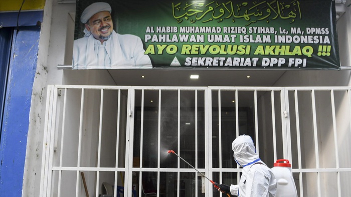 Anggota kepolisian dengan mengenakan hazmat menyemprotkan cairan disinfektan di kawasan Petamburan III, Jakarta Pusat, Minggu 22 November 2020.  (Foto: Antara/M Risyal Hidayat)