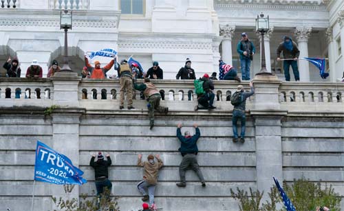 Pendukung Presiden Donald Trump memanjat dinding barat Capitol di Kota di Washington, AS pada Rabu, 6 Januari 2021. (Foto AP / Jose Luis Magana)