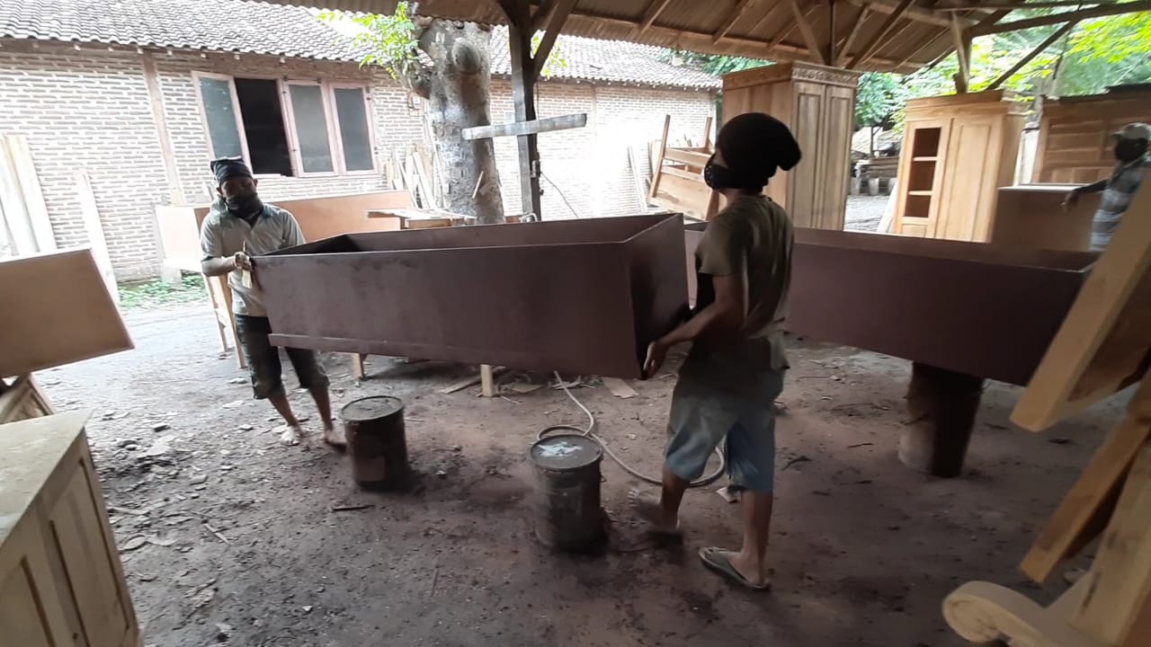 Sejumlah pekerja sedang menyelesaikan peti-peti mati di tempat mebel milik Abdul Muni. (Foto: Ikhsan Mahmudi/Ngopibareng.id)