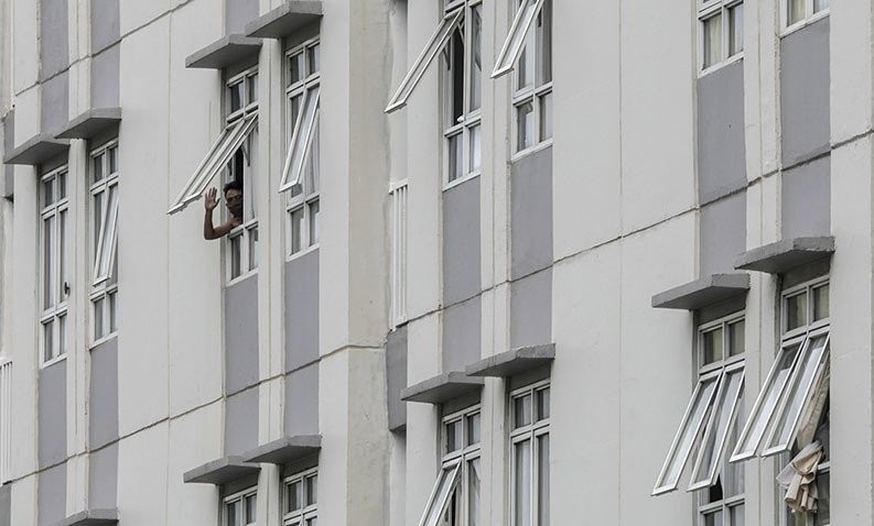 Pasien COVID-19 melambaikan tangan dari satu tower di Rumah Sakit Darurat Penanganan COVID-19 Wisma Atlet Kemayoran di Jakarta. (Foto: Antara/Ariella Annasya)