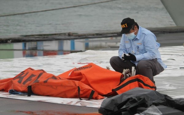 Seorang petugas di depan kantong Jenazah yang baru diturunkan dari kapal di Dermaga IJCT Tanjung Priok, Jakarta. (Foto: Asmanu Sudharso/Ngopibareng.id)