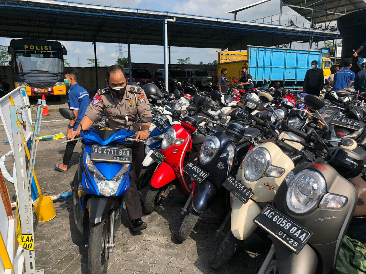 Polisi menuntun salah satu motor yang disita dari arena balap liar. Ngopibareng.id)