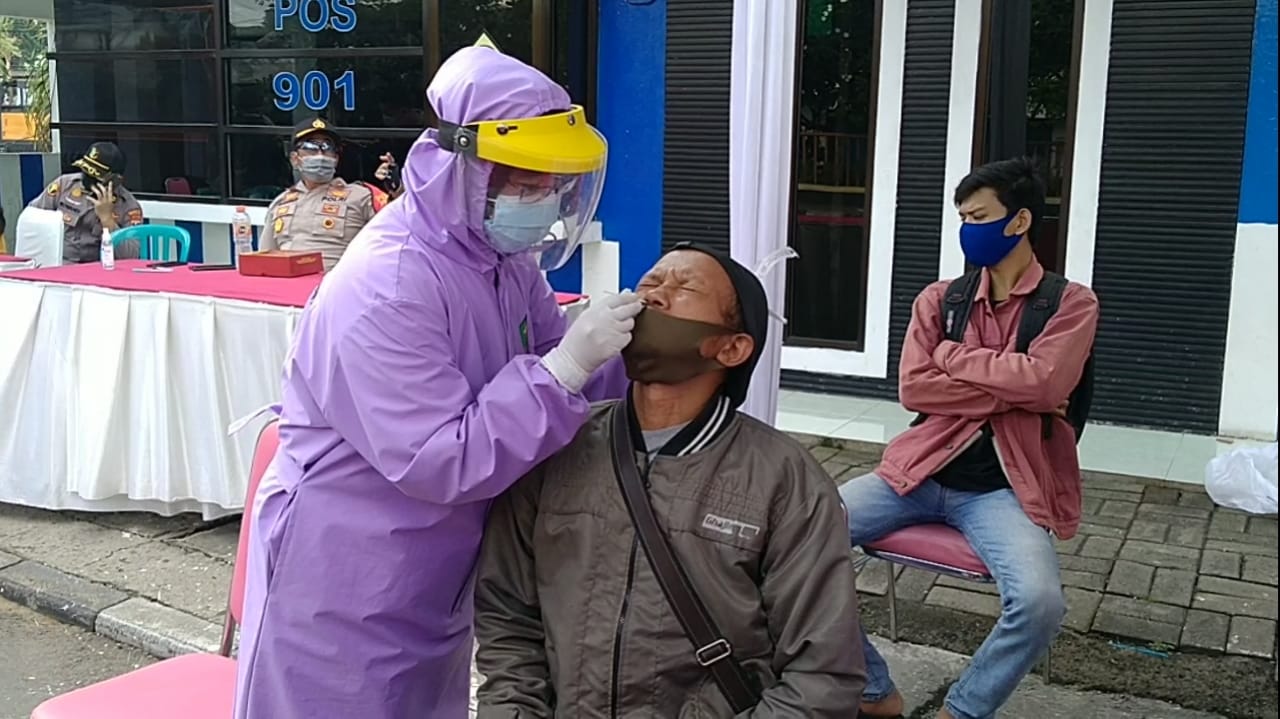 Salah satu pengendara yang dihentikan, Mukotib, menjalani rapid antigen setelah dihentikan oleh petugas di Posko Waru, Sidoarjo, Jumat 12 Februari 2021. (Foto: Fariz Yarbo/Ngopibareng.id)