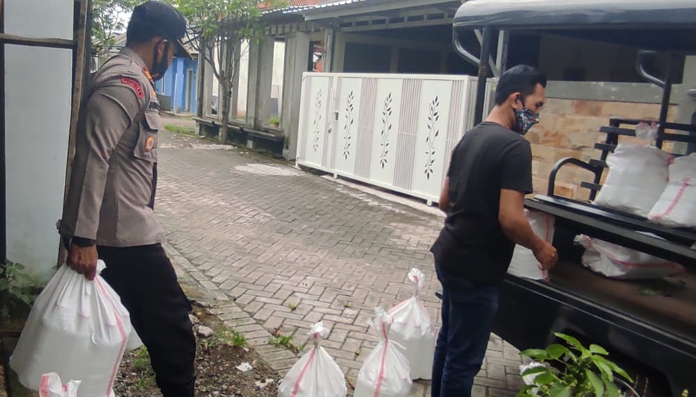 Kapolsek Pesanggaran AKP Subandi membawa karung berisi minuman keras yang disita dari rumah EW. (Foto: Istimewa)