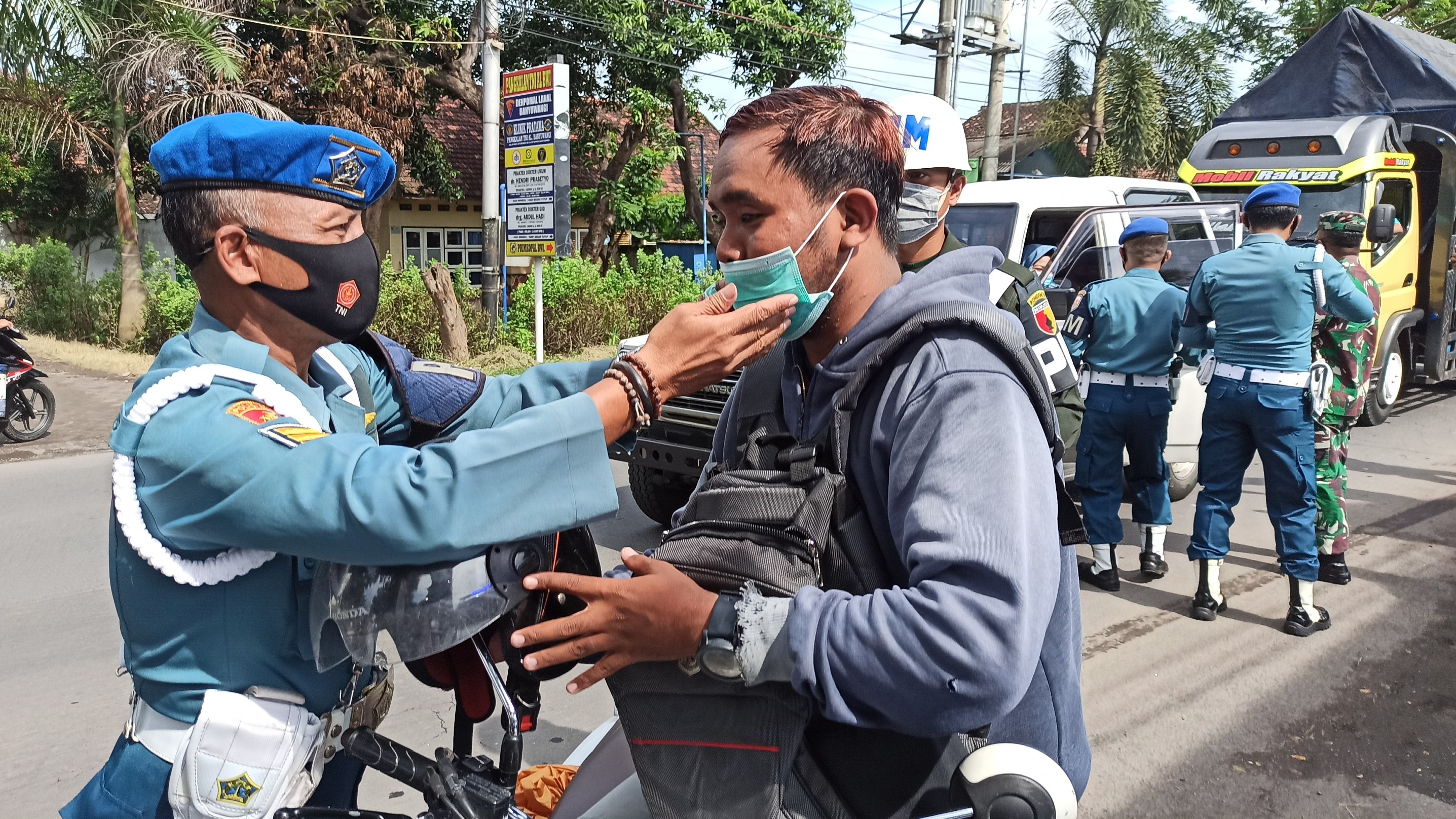 Anggota POMAL Lanal Banyuwangi memasangkan masker pada pengguna jalan (Foto: Muh Hujaini/Ngopibareng.id)