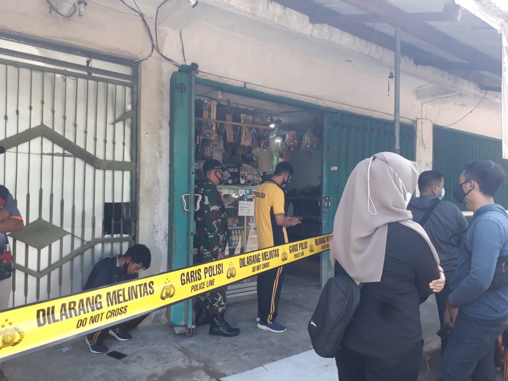 Pihak kepolisian melakukan olah tempat kejadian perkara dengan garis polisi melintang di area depan toko korban tewas. (Foto: Choirul Anam/Ngopibareng.id)