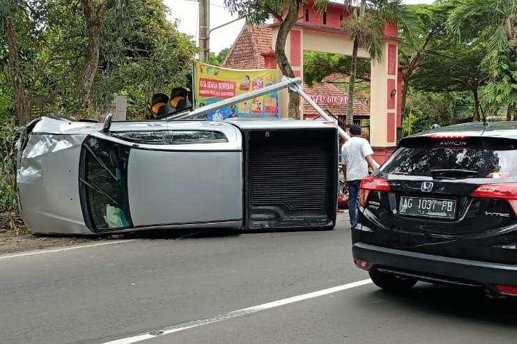 Mobil Mitsubishi Estrada terguling setelah menabrak 3 pengemudi sepea motor dan tiang lampu di Gurah, Kediri. (Foto: Istimewa)