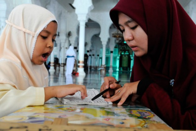 Seorang guru ngaji dengan sabar sedang mendidik santrinya. (Foto: Istimewa) 