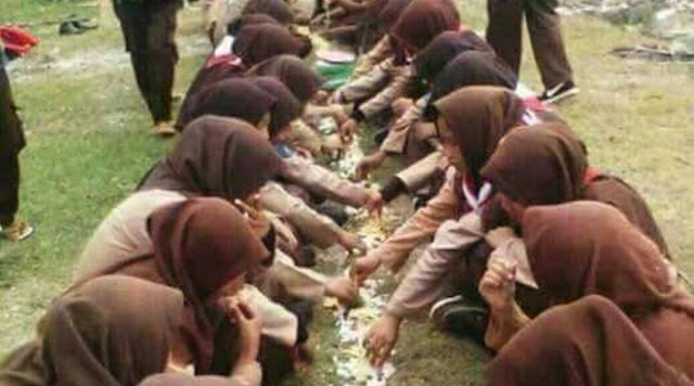 Tersebar foto anggota Pramuka tengah menyantap makanan beralaskan tanah.