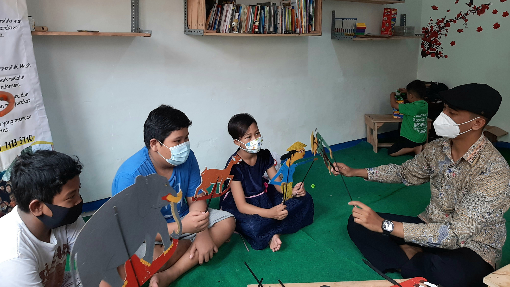 Hilmi Ramadhan (memakai topi) sedang mengajarkan wayang pada anak-anak kampung Lemah Putro Surabaya. (Foto: Pita Sari/Ngopibareng.id(