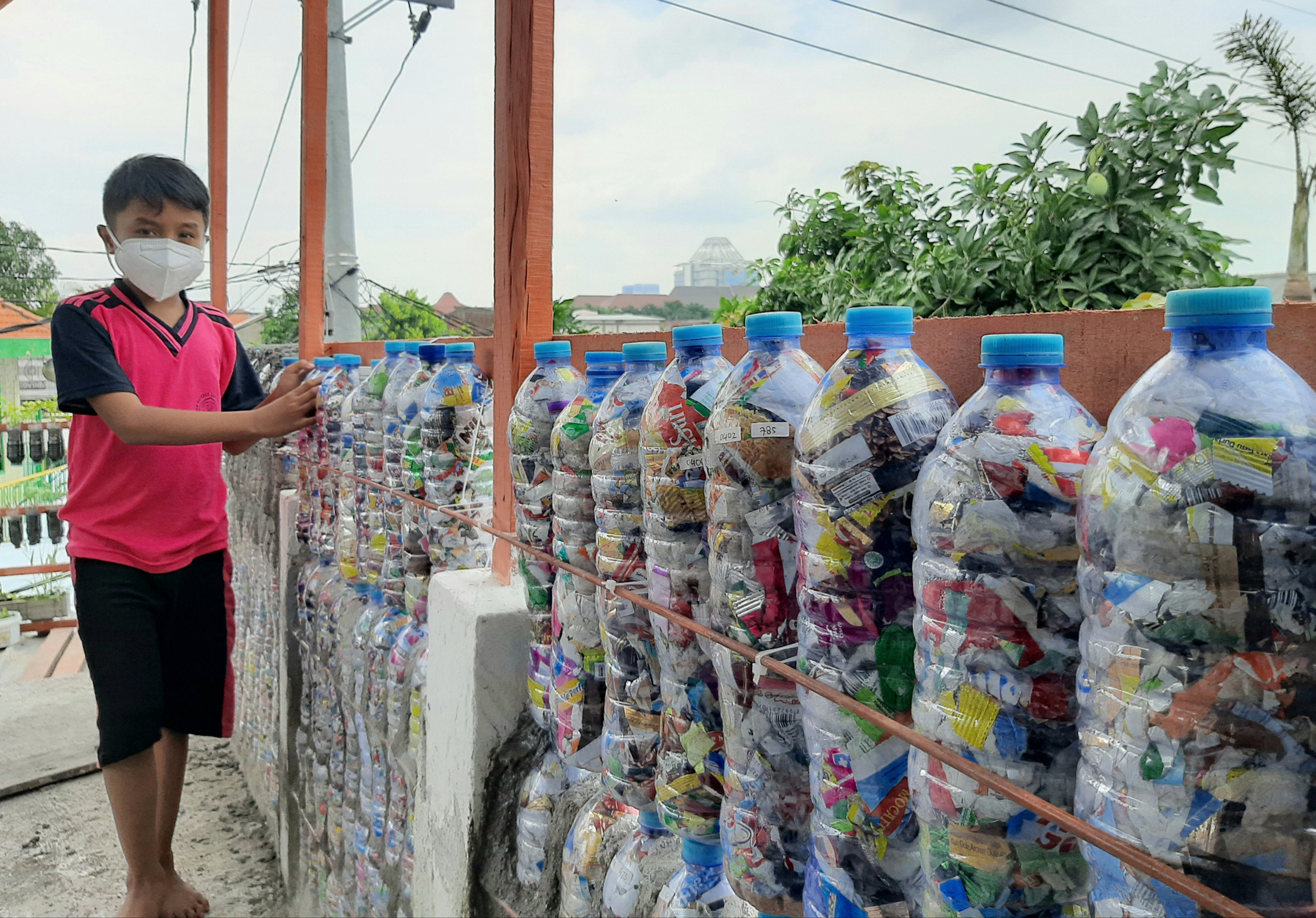 Ahmad Arkaan Taamir saat menunjukan ecobrick buatanya yang dijadikan dinding. (Foto: Pita Sari/Ngopibareng.id)