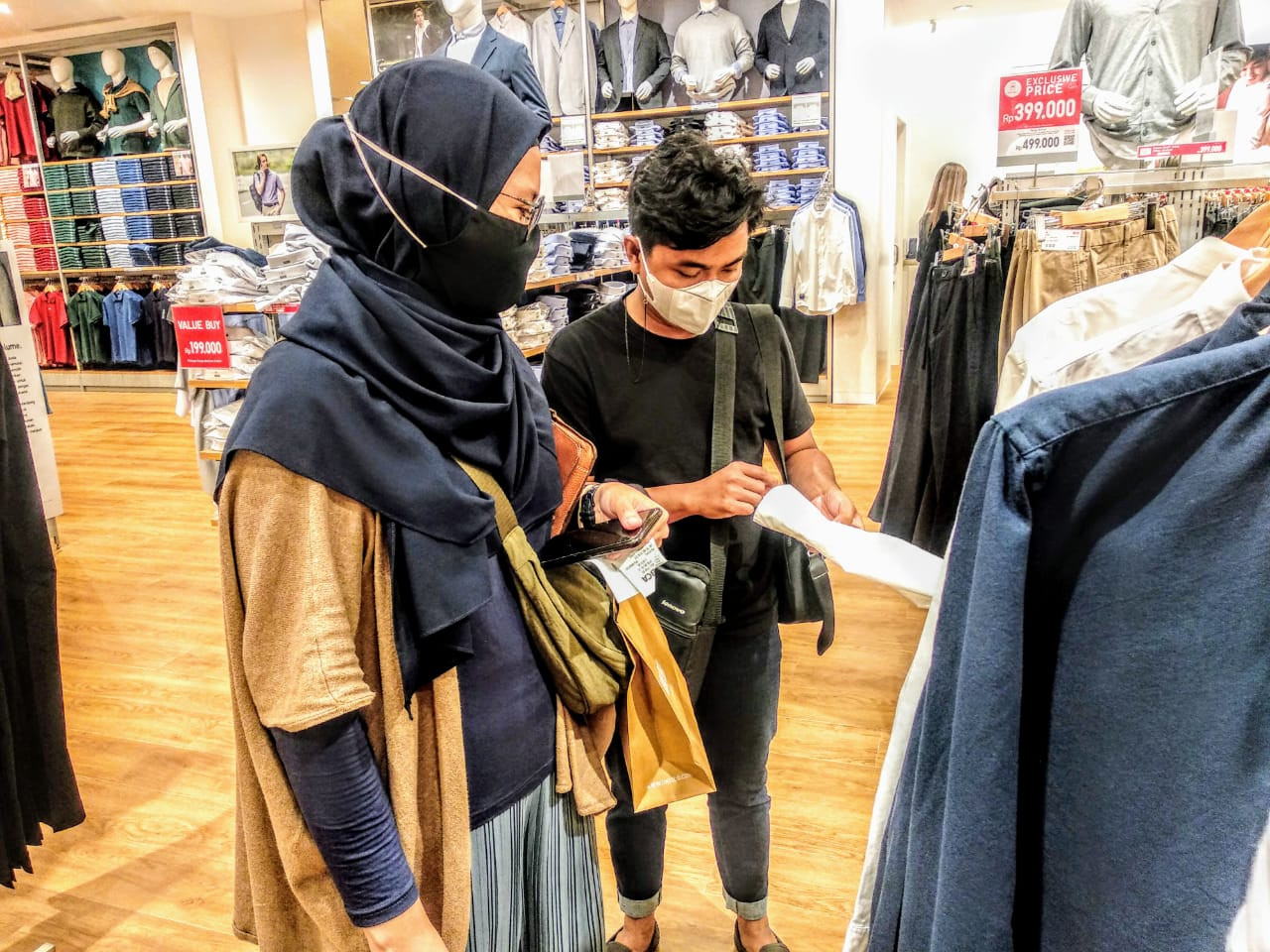 Gilang Ramadhan (kaos hitam) saat memilih atasan di gerai Uniqlo lantai satu Ciputra World Surabaya (Foto: Mutqiyyah Rizqi/Ngopibareng.id)