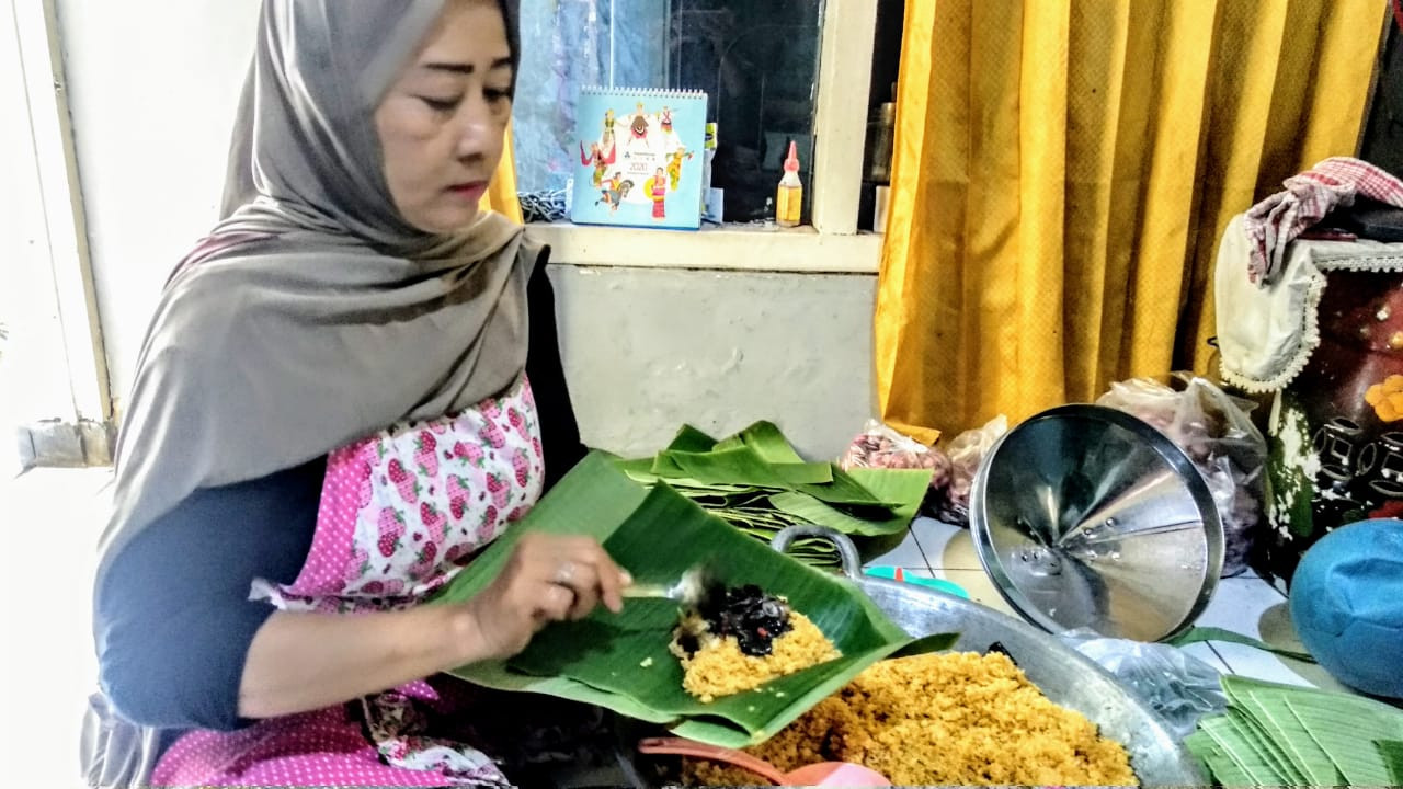 Emil Kusmariati saat membungkus nasi bakar cumi di kediamannya, Bulaksari Gang 1 Surabaya. (Foto: Mutqiyyah Rizqi/Ngopibareng.id)