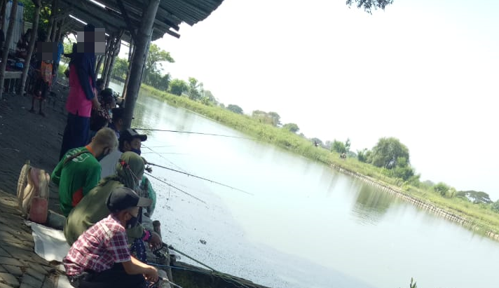 Anak-anak hingga orang dewasa menikmati wisata di kolam pancing dengan memakai masker sesuai protokol kesehatan. (Fotoo: Yasmin Fitrida/Ngopibareng.id)