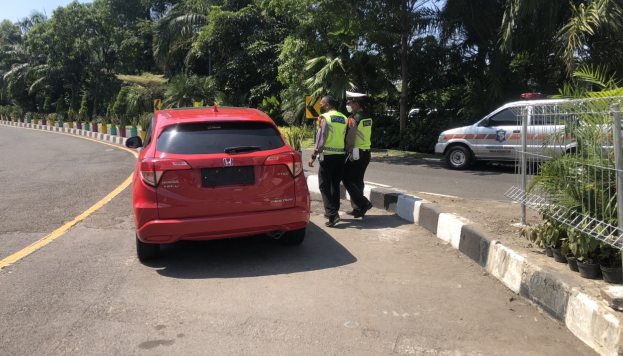 Petugas pos penyekatan Bundara Waru memberhentikan sebuah mobil (Foto: Andhi Dwi/Ngopibareng.id)