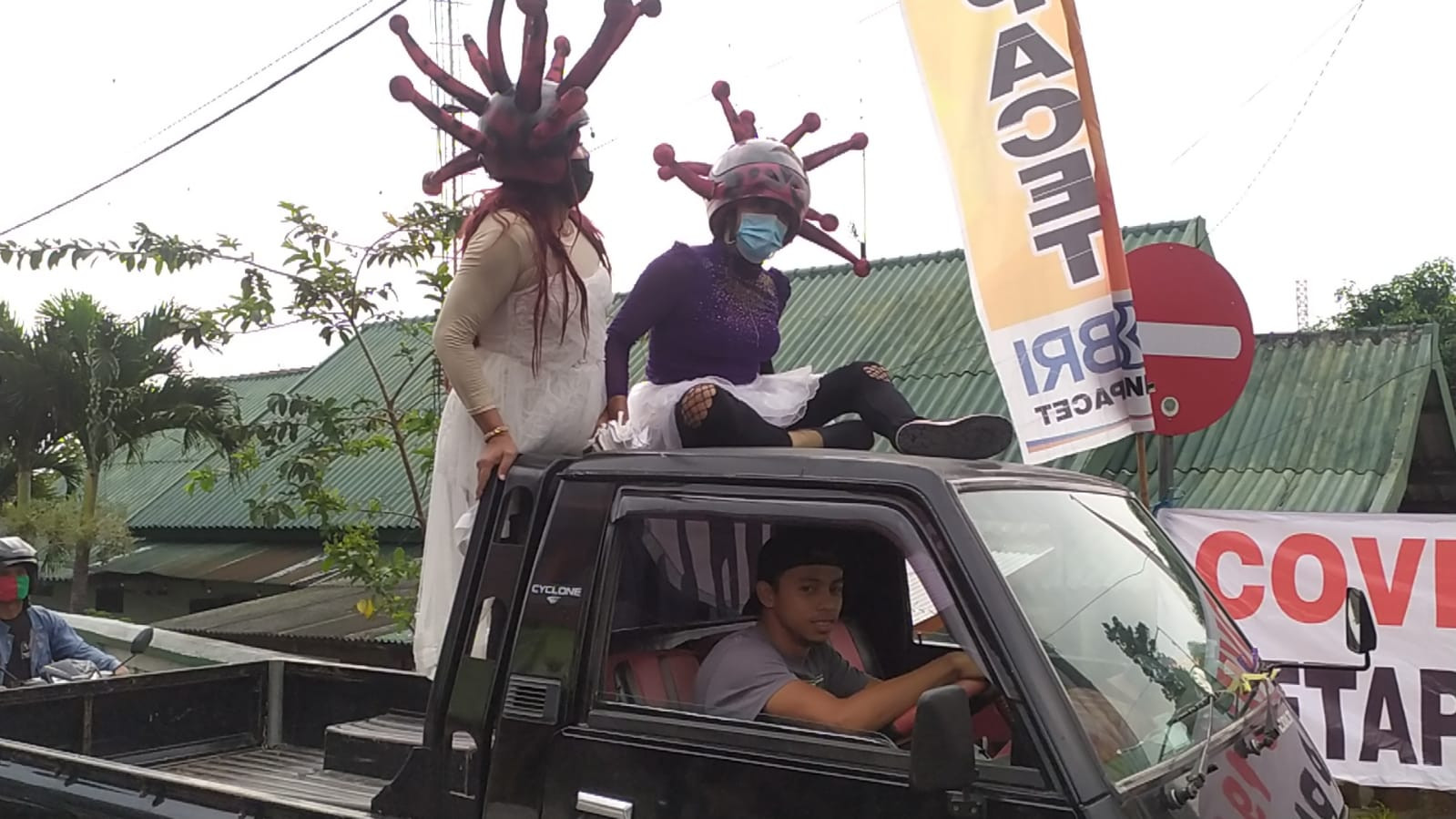 Pocong Covid-19 dan maskot Covid-19 di Mojokerto ini naik ke atap mobil pengendara pick up yang tak mengenakan masker. (Foto: Deny Lukmantara/Ngopibareng.id)