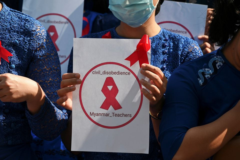 Seorang guru dari Yangon University of Education memegang tanda dengan pita merah saat mengikuti demonstrasi menentang kudeta militer di Yangon, Myanmar, 5 Februari 2021. (Foto: reuters)