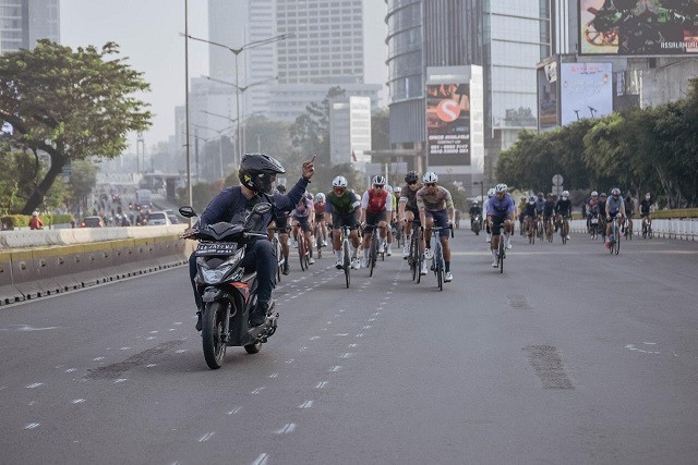 Seorang pengendara motor mengacungkan jari tengah kepada para pesepeda yang menghalangi jalan raya. (Foto: Twitter)