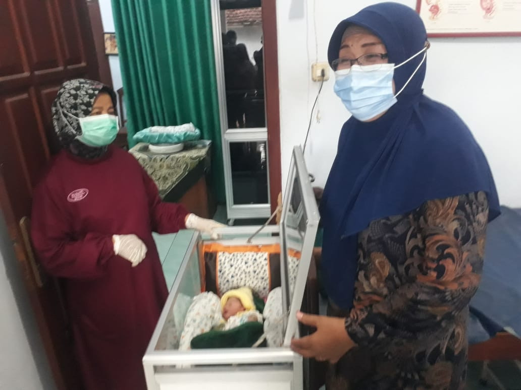 Wasiti, bidan Desa Ngoran Kecamatan Nglegok, Kabupaten Blitar bersama Marsiati orang tua keluarga yang berminat untuk merawat bayi perempuan yang dibuang beralas daun pisang. Penemuan ini sempat menghebohkan warga Desa Ngoran Kecamatan Nglegok, Kabupaten Blitar kemarin, Jumat Jumat, 04 Juni 2021.  (Foto: Choirul Anam/Ngopibareng.id)