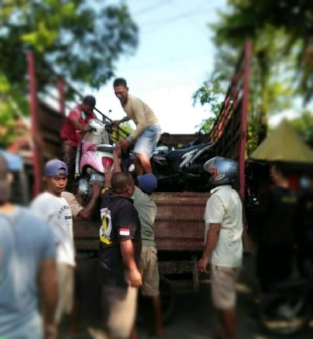 Polisi dibantu warga menaikkan motor yang ditnggal pemiliknya di sekitar arena judi sabung ayam (Foto: Istimewa)